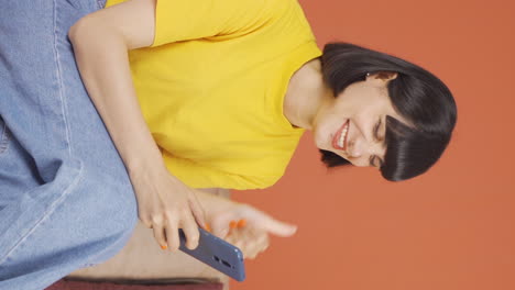 Vertical-video-of-The-young-woman-looking-at-the-phone-is-happy.